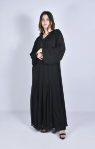 Studio fashion shoot of a woman wearing a black abaya and high heels.
