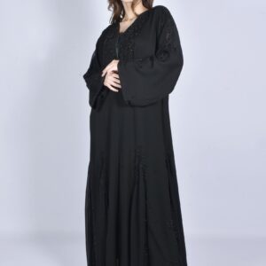 Studio fashion shoot of a woman wearing a black abaya and high heels.